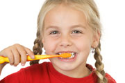 Ein kleines Mädchen putzt sich grinsend seine Zähne